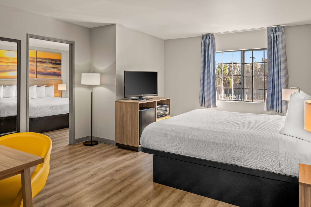 Une chambre d’hôtel équipée d’un lit, d’un bureau, d’une chaise, d’une télévision et d’une fenêtre avec des rideaux.