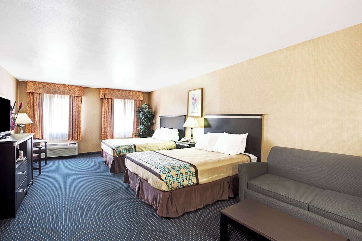 Une chambre d’hôtel avec deux lits, un canapé, un bureau et une télévision.