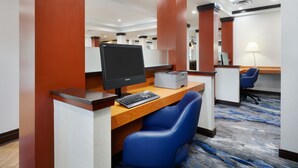 Quarto de hotel com escrivaninha, computador e cadeira.