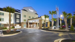 Um hotel Fairfield by Marriott com design moderno, apresentando uma entrada destacada, palmeiras e uma área de estacionamento.