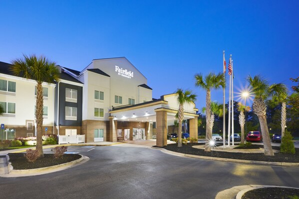 A Fairfield by Marriott hotel with a modern entrance, palm trees, and a parking lot.