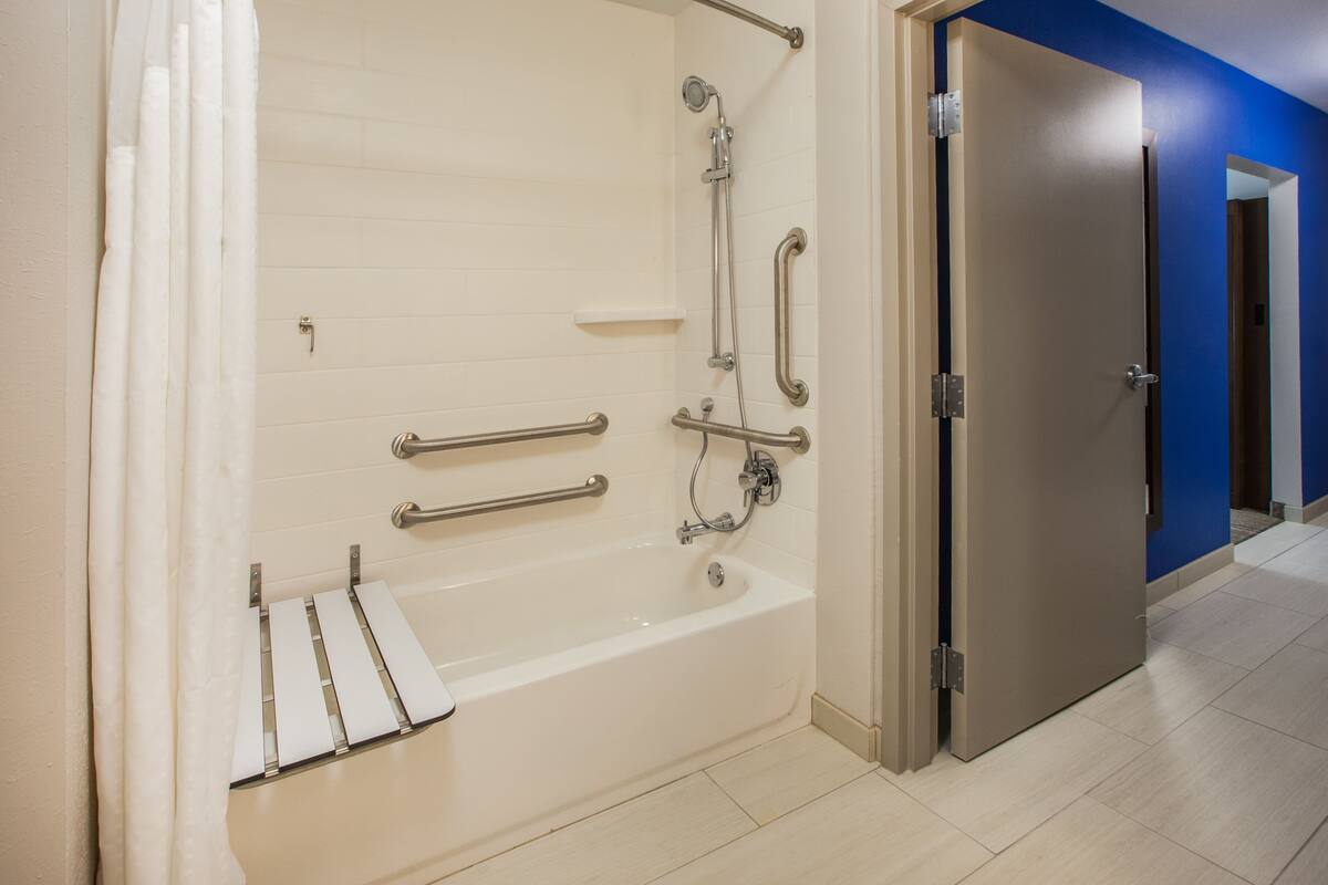 A modern bathroom with a walk-in bathtub, grab bars, and a showerhead.