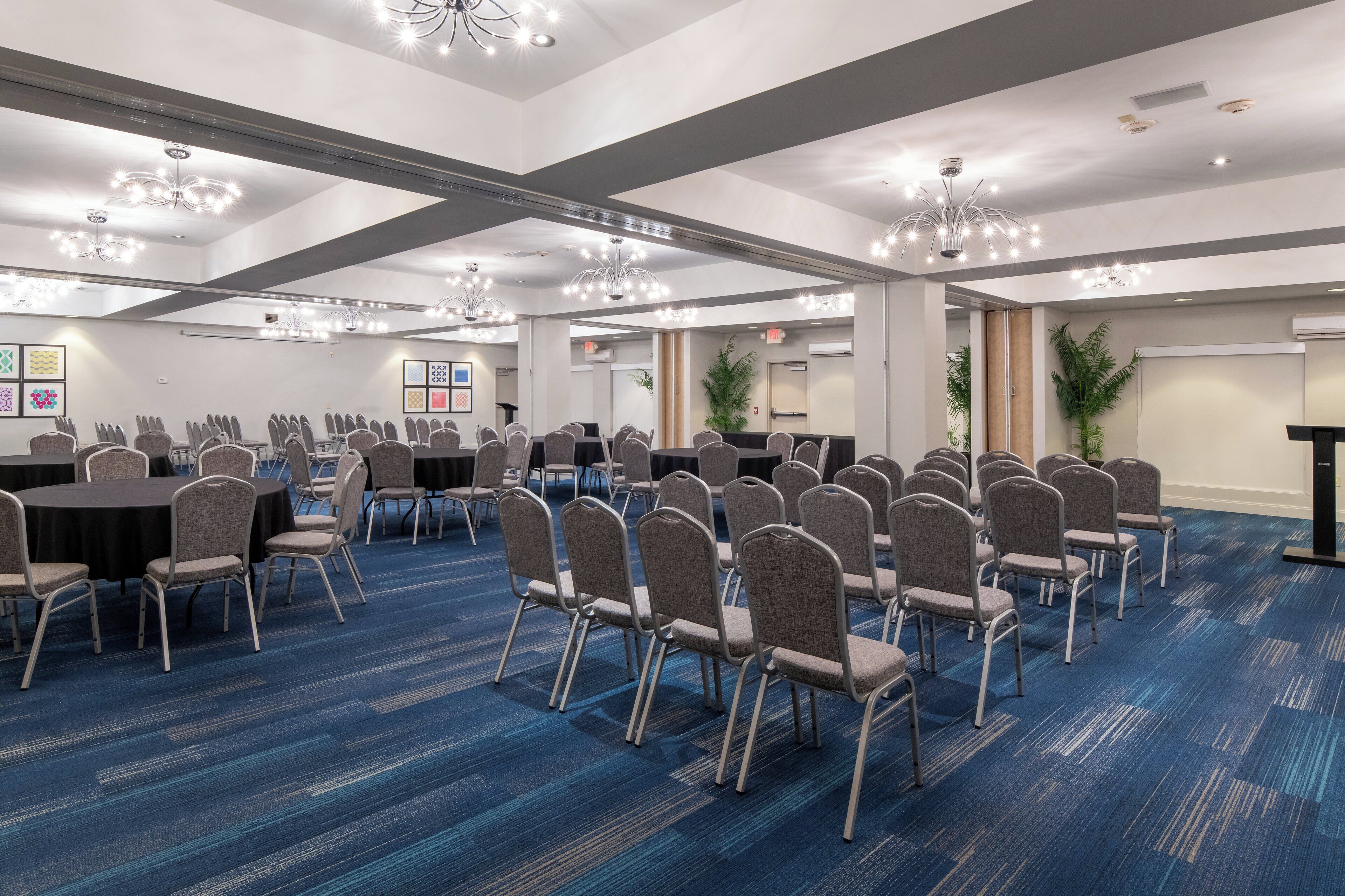 A conference room with rows of chairs, tables, and a blue carpeted floor.