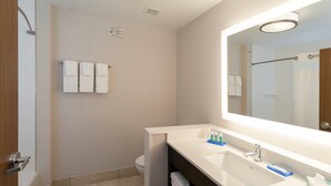 A modern bathroom with a large mirror, two sinks, and a shower.