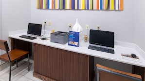 A reception desk with two laptops, a printer, a vase, and a sign indicating more to love.
