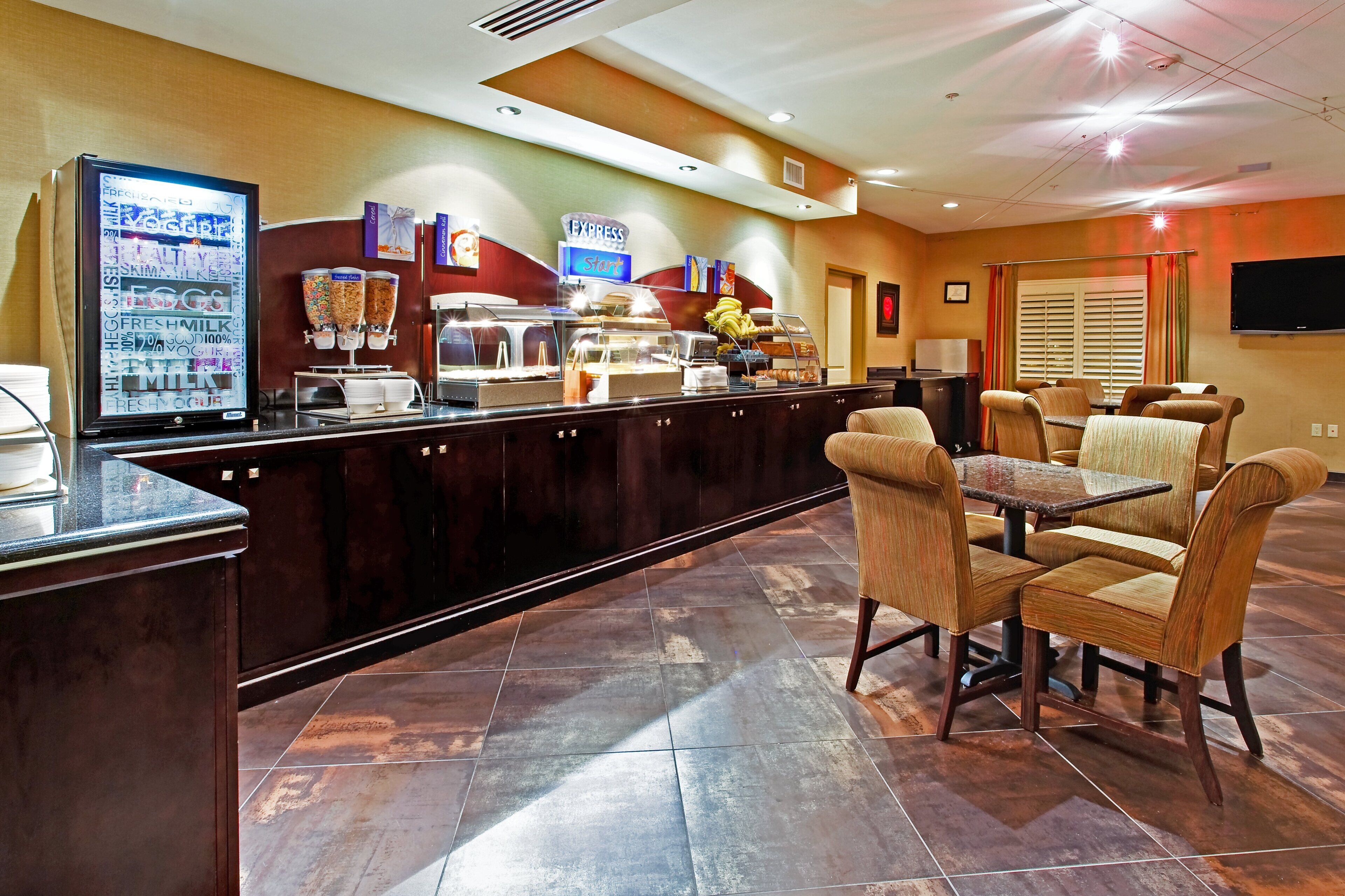 Un área de desayuno de hotel con mostrador, asientos y televisor.