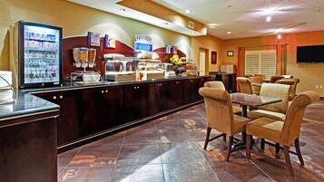 Un área de desayuno de hotel con mostrador, asientos y televisor.