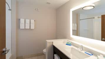 A modern bathroom with a shower, toilet, and a large mirror above a sink.
