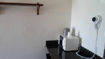 A room with a black countertop, a white microwave, a coffee maker, and a wall-mounted security camera.