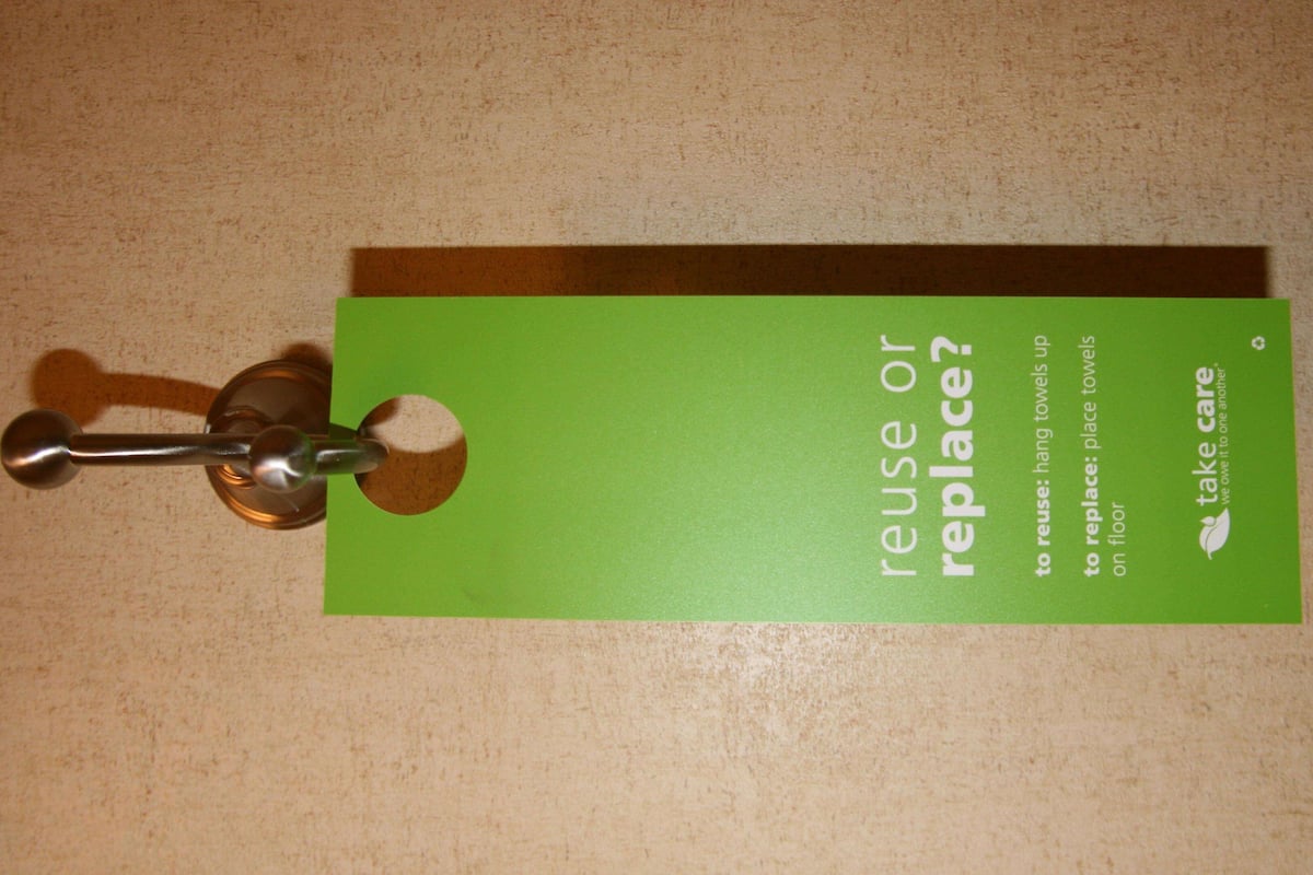 A green card with the text "reuse or replace?" and instructions for hanging towels on a floor.