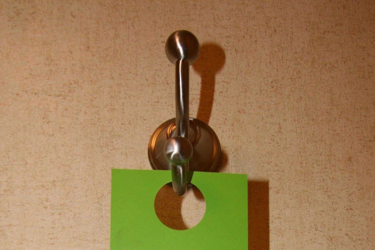 A green card with the text "reuse or replace?" and instructions for hanging towels on a floor.