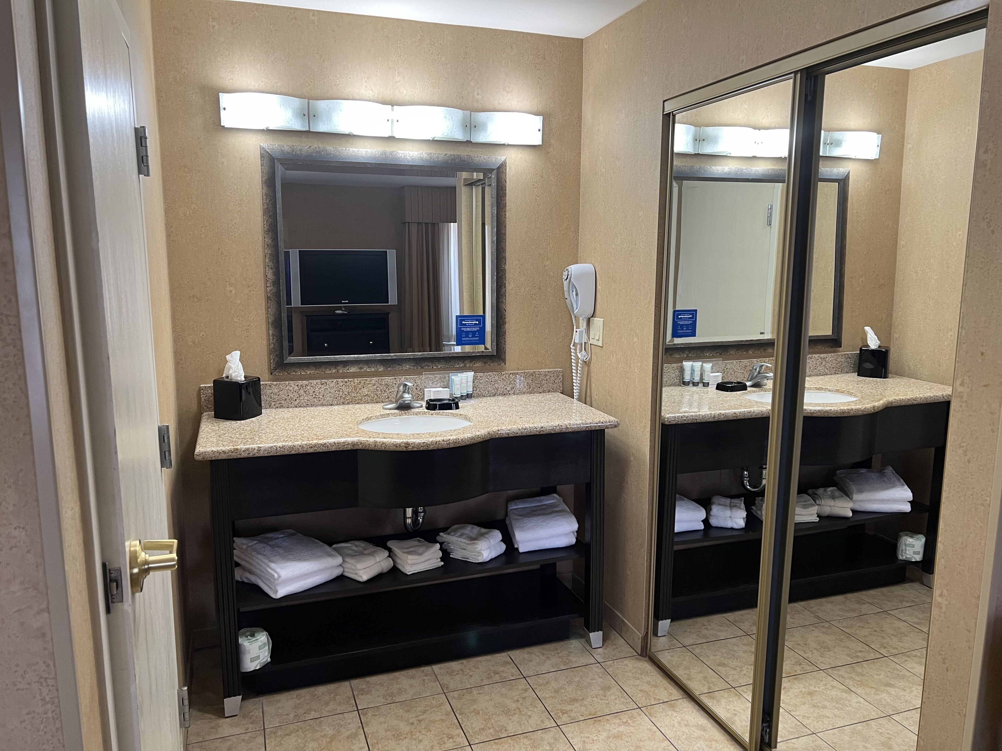 Une salle de bain d’hôtel avec deux lavabos, un sèche-cheveux et un miroir.