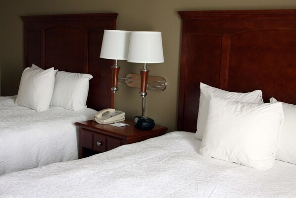 A hotel room with two beds, a wooden headboard, a bedside table with a telephone and a radio, and a wall-mounted lamp. - Hampton Inn & Suites Paducah (Paducah)