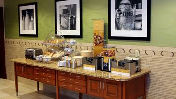A breakfast buffet with various food items and coffee machines.