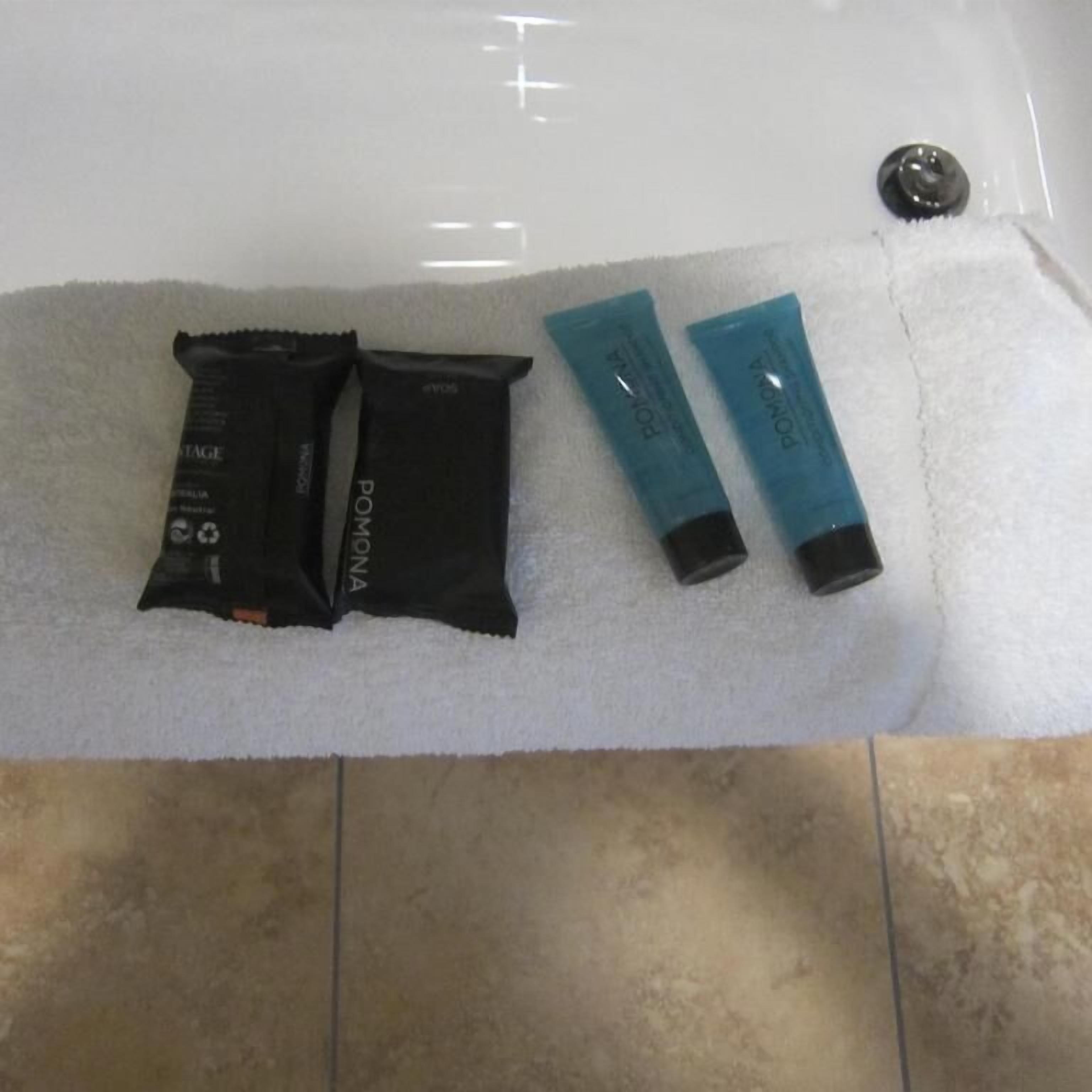 A bathroom with a white towel and two black and two blue toiletries on a white towel.