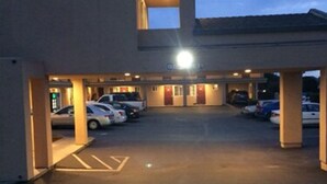 A parking lot with several cars parked, a building with a flat roof, and a sign that reads "OPEN". - Pacific Best Inn (Seaside)