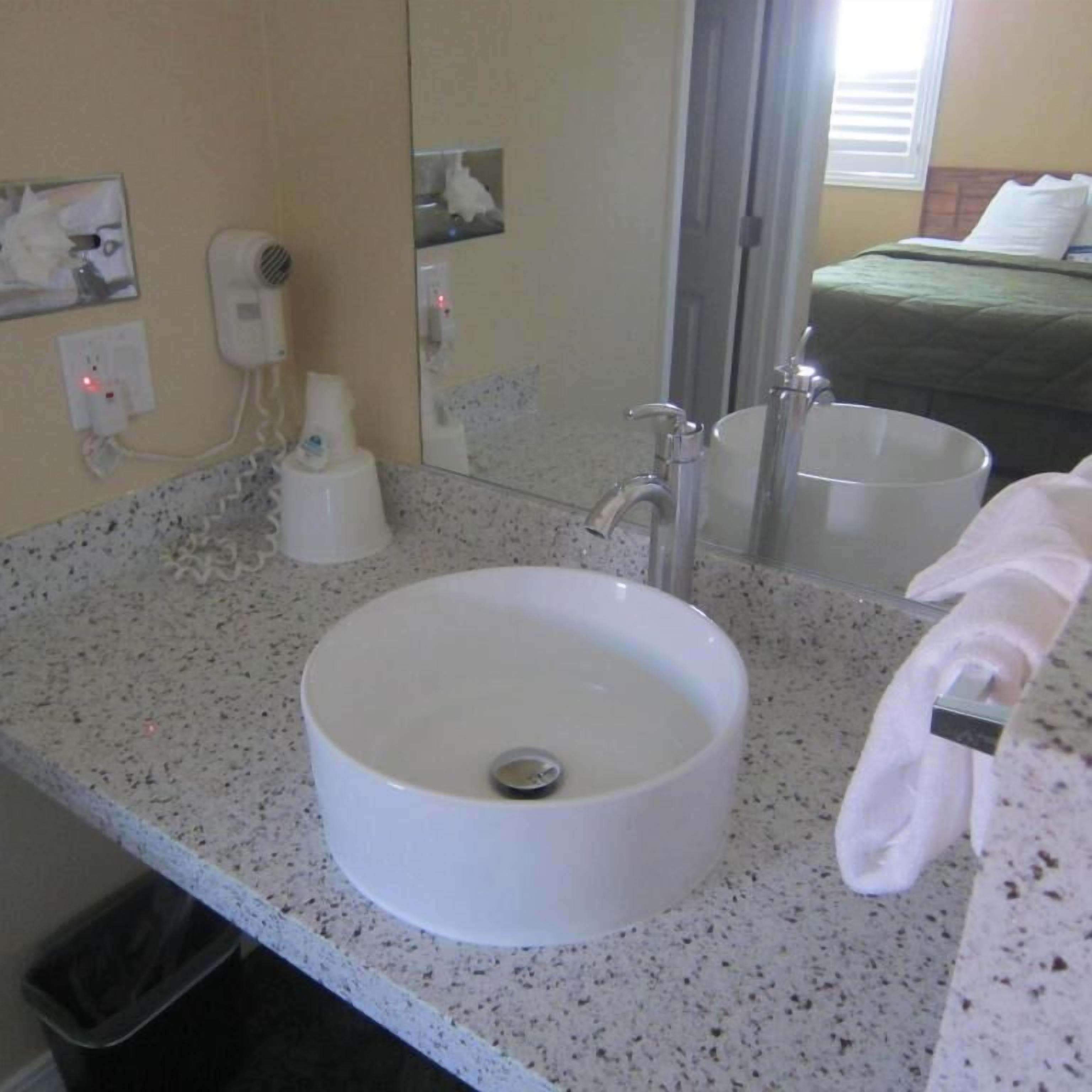 A bathroom with a white sink, a mirror, a towel rack, and a toilet.
