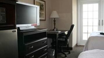 A hotel room with a bed, a desk, a chair, a television, and a dresser.