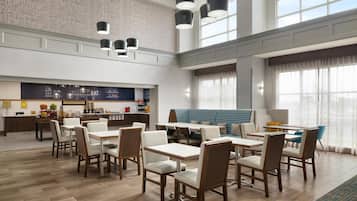 A spacious dining area with high ceilings, pendant lighting, and a view of the city through large windows.