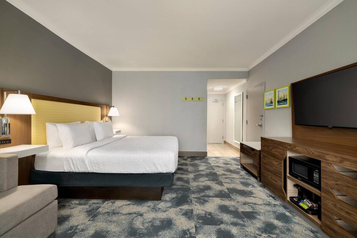 A hotel room with a bed, bedside lamps, a television, a microwave, and a desk.