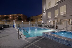 Una piscina al aire libre, sillones reclinables de piscina