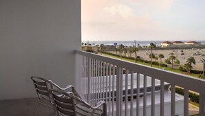 Een balkon met uitzicht op een parkeerplaats en strand.