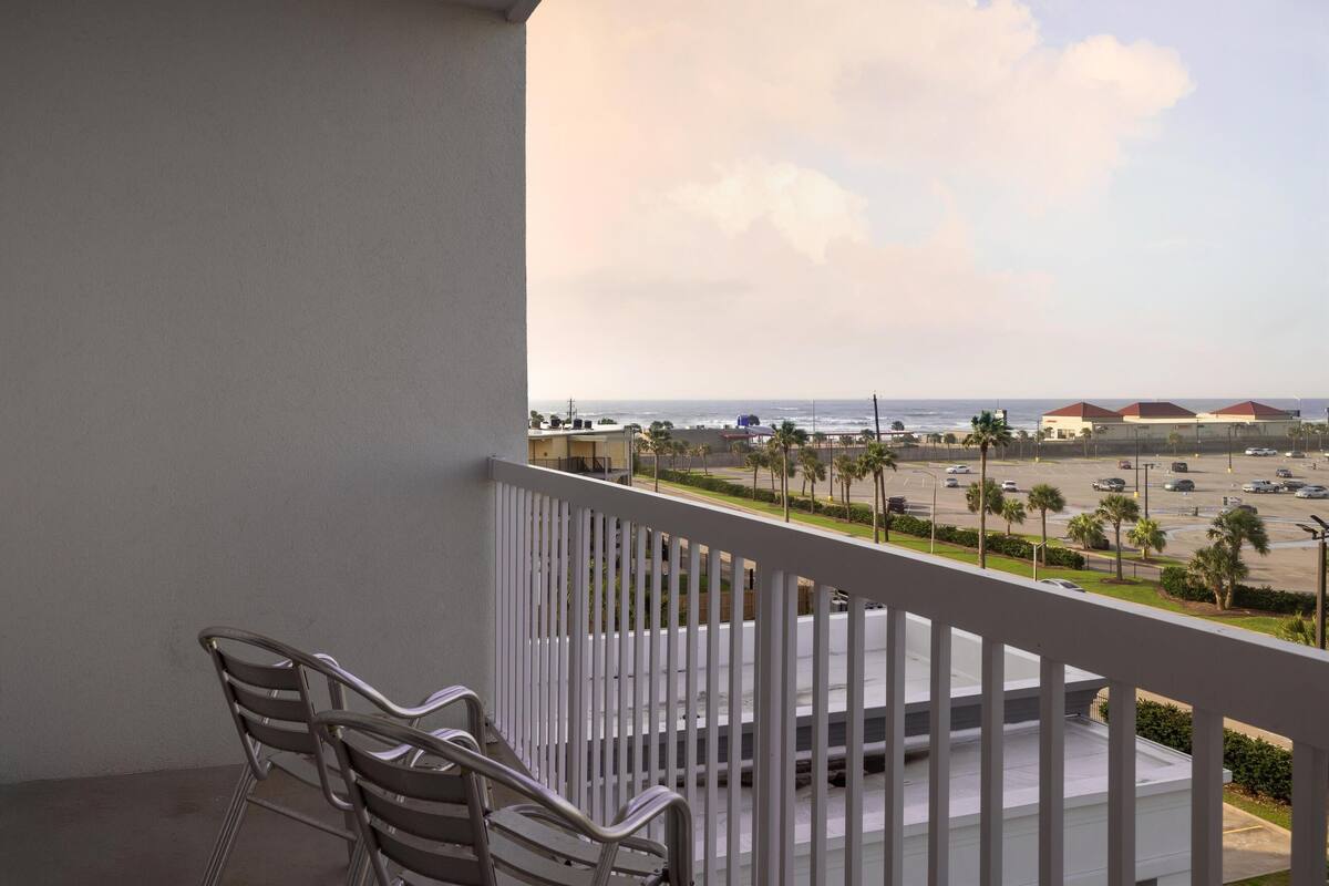A balcony with a view of a parking lot and beach.