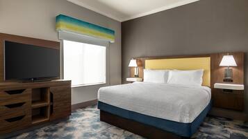 A hotel room with a bed, a TV, a desk, and a window.
