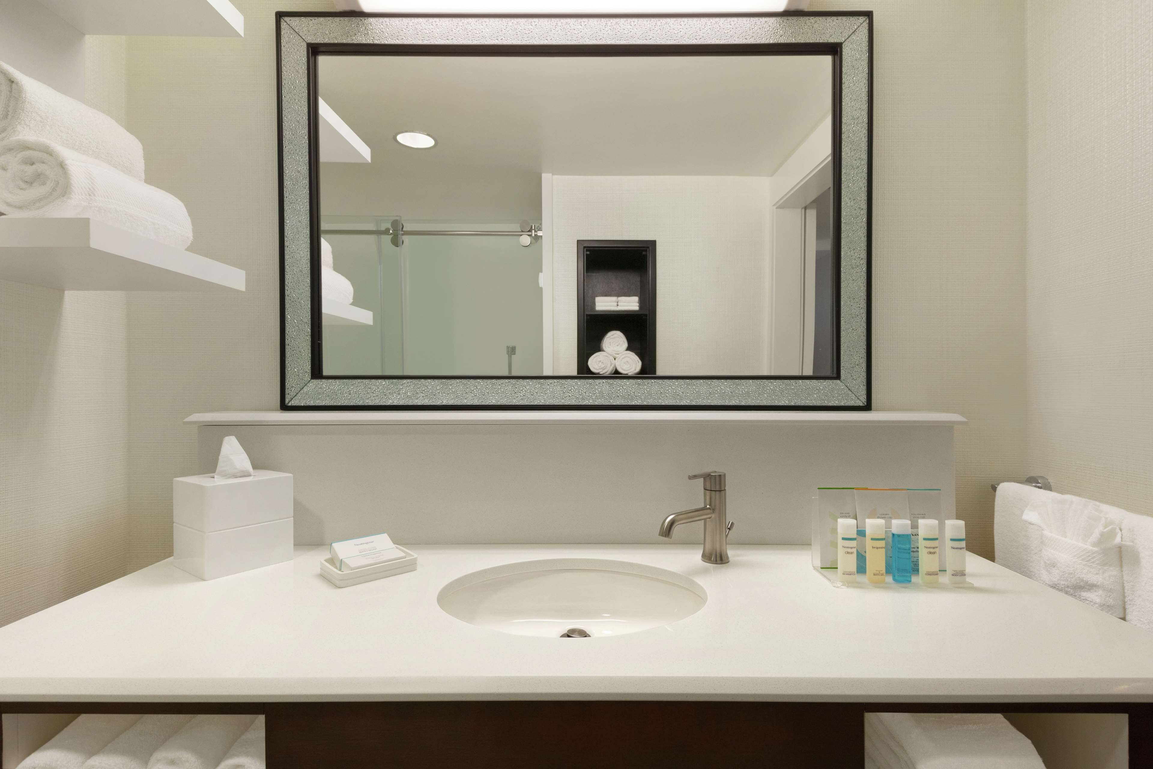 A modern bathroom with a large mirror, a sink, and a towel rack.