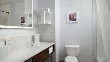 Un baño moderno con un lavabo blanco, espejo e inodoro. Hay un perchero y un cuadro en la pared.