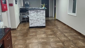 A spacious reception area with a marble counter, a clock on the wall, and a fire extinguisher.