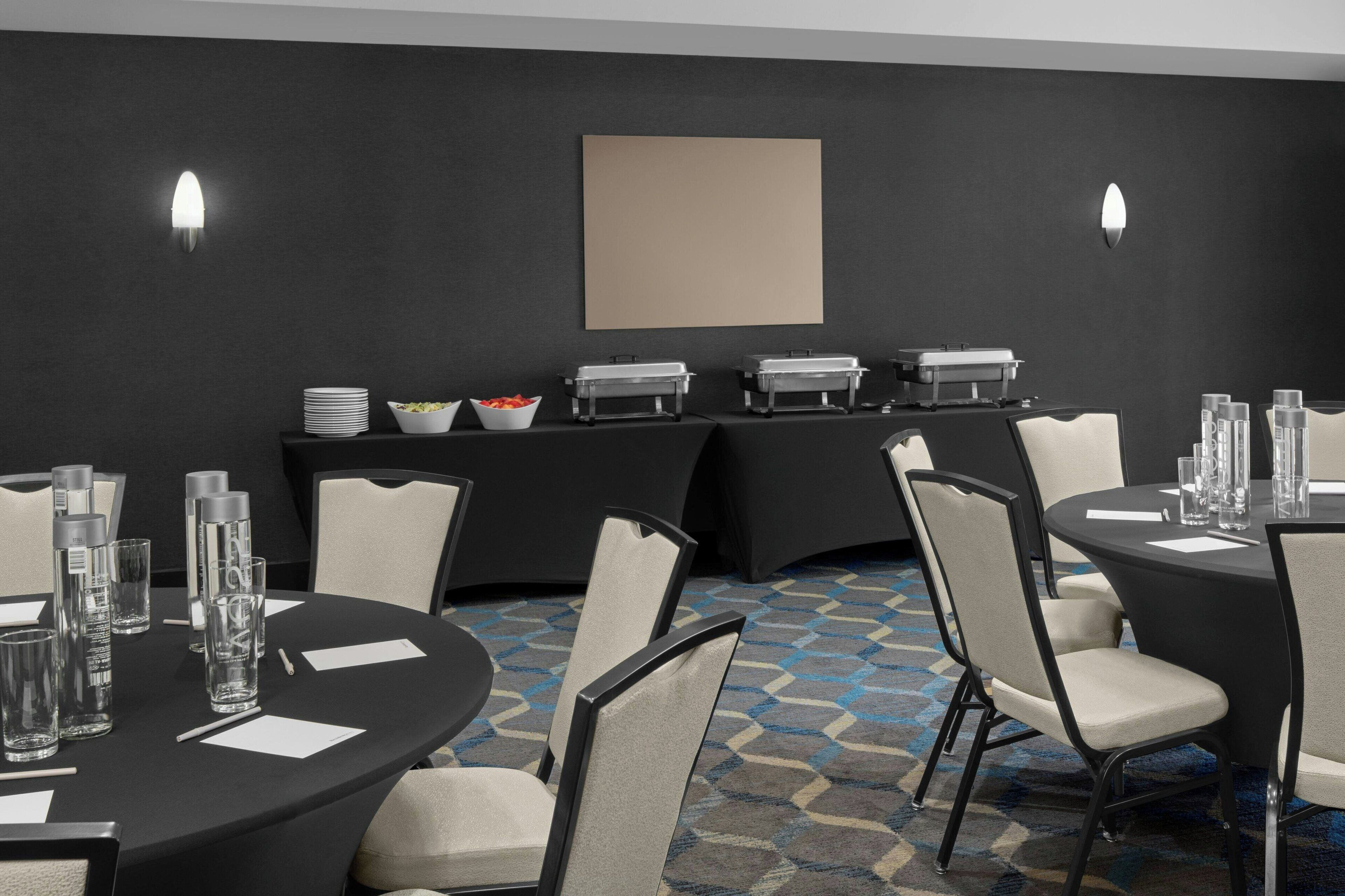 Un salón de conferencias con mesas redondas, sillas y estaciones de buffet.