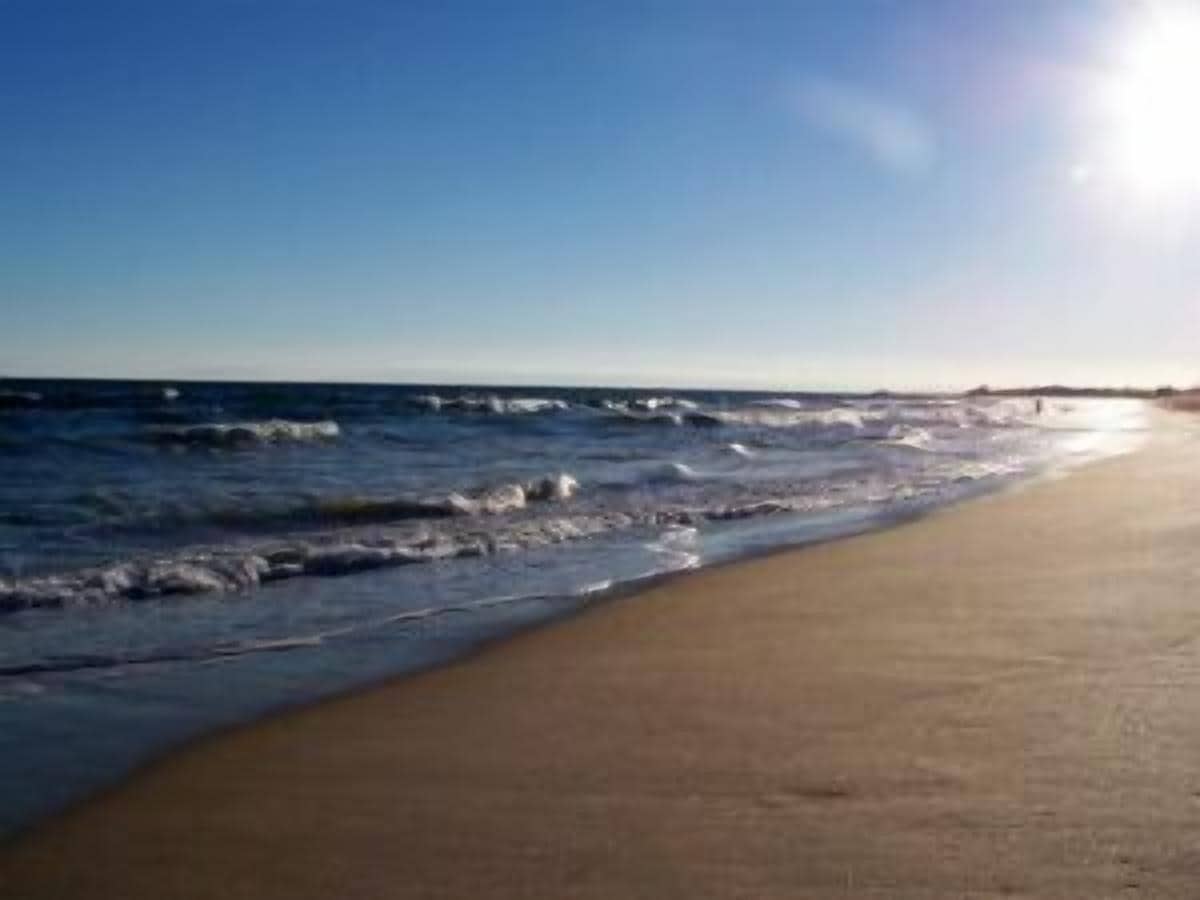 A beach with waves and a clear sky.