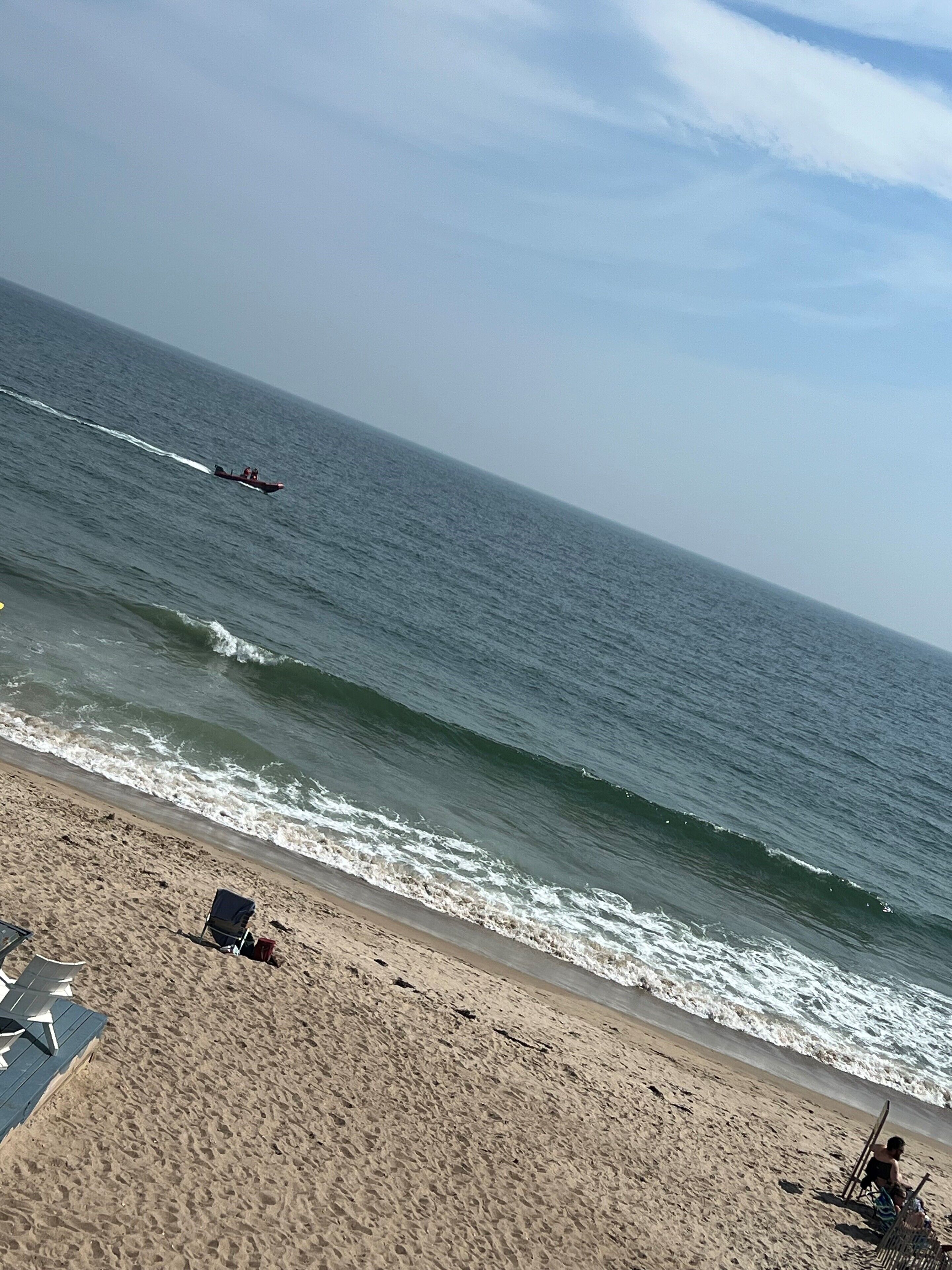 Une plage avec un bateau sur l’eau, un rivage sablonneux et un ciel dégagé.