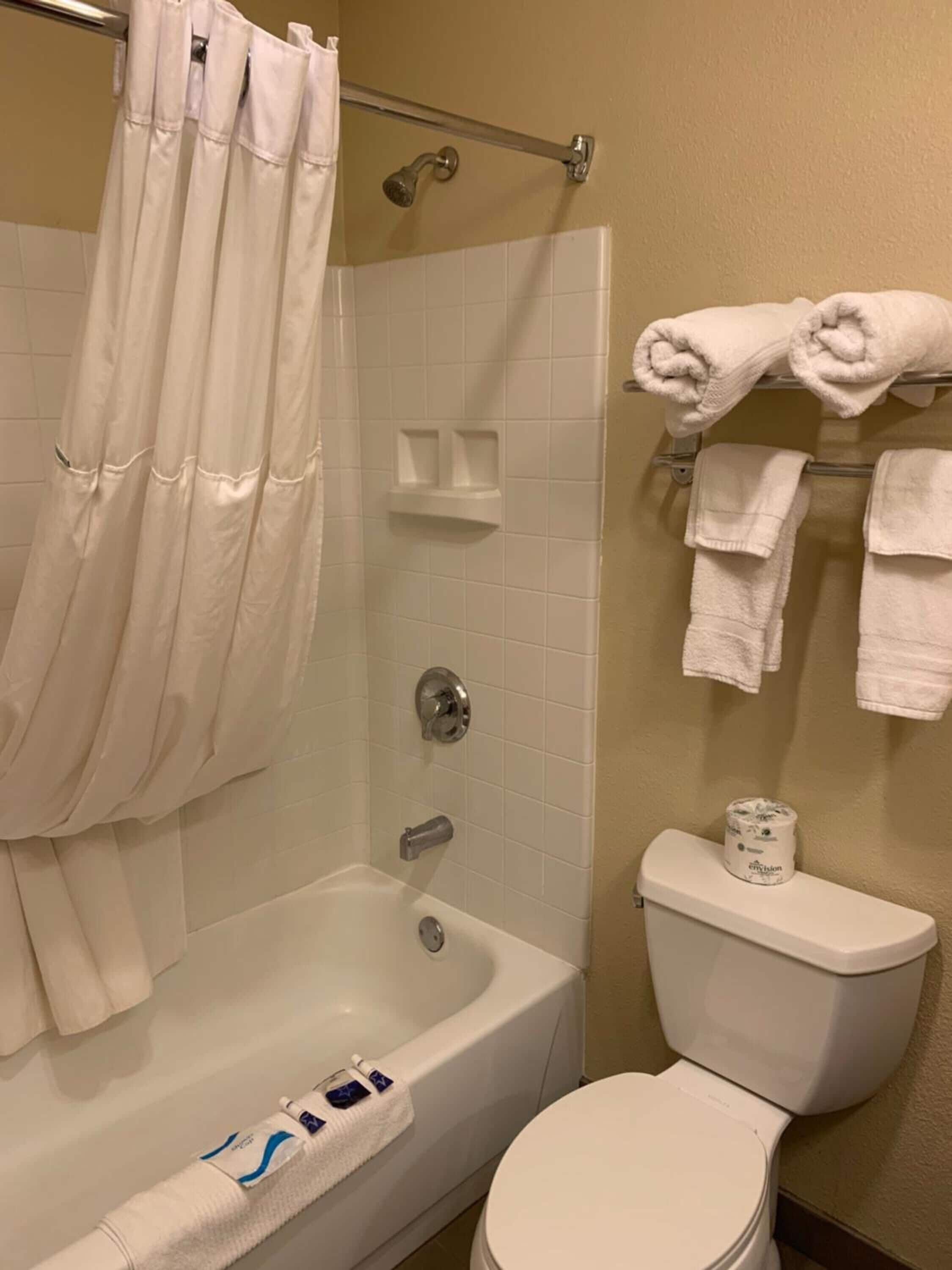 Un baño con bañera, inodoro y cortina de ducha.
