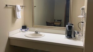 Un bany amb un rentapeus blanc, un mirall i una cafetera.