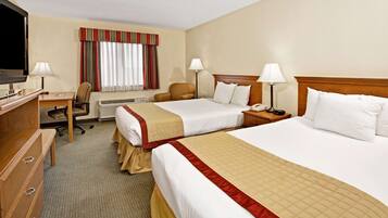 A hotel room with two beds, a desk with a TV, a chair, and a dresser.