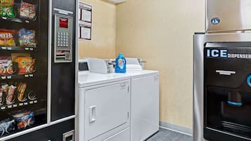 A laundry area with a vending machine, a washing machine, and an ice dispenser.