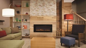 A modern living room with a fireplace, wooden shelving, a sofa, a coffee table, and a chair. - Country Inn & Suites by Radisson, Washington, D.C. East - Capitol Heights, MD (Capitol Heights)