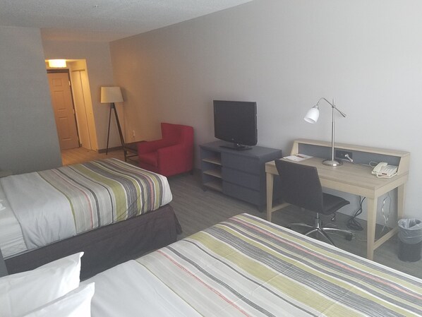 Una habitación de hotel con una cama, un escritorio con una computadora, un televisor y una silla.
