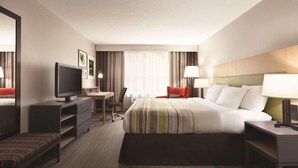 A hotel room with a bed, a desk, a TV, a chair, and a bench. - Country Inn & Suites by Radisson, Washington, D.C. East - Capitol Heights, MD (Capitol Heights)