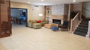 A spacious living area with a sofa, a coffee table, a TV, and a staircase. - Country Inn & Suites by Radisson, Washington, D.C. East - Capitol Heights, MD (Capitol Heights)