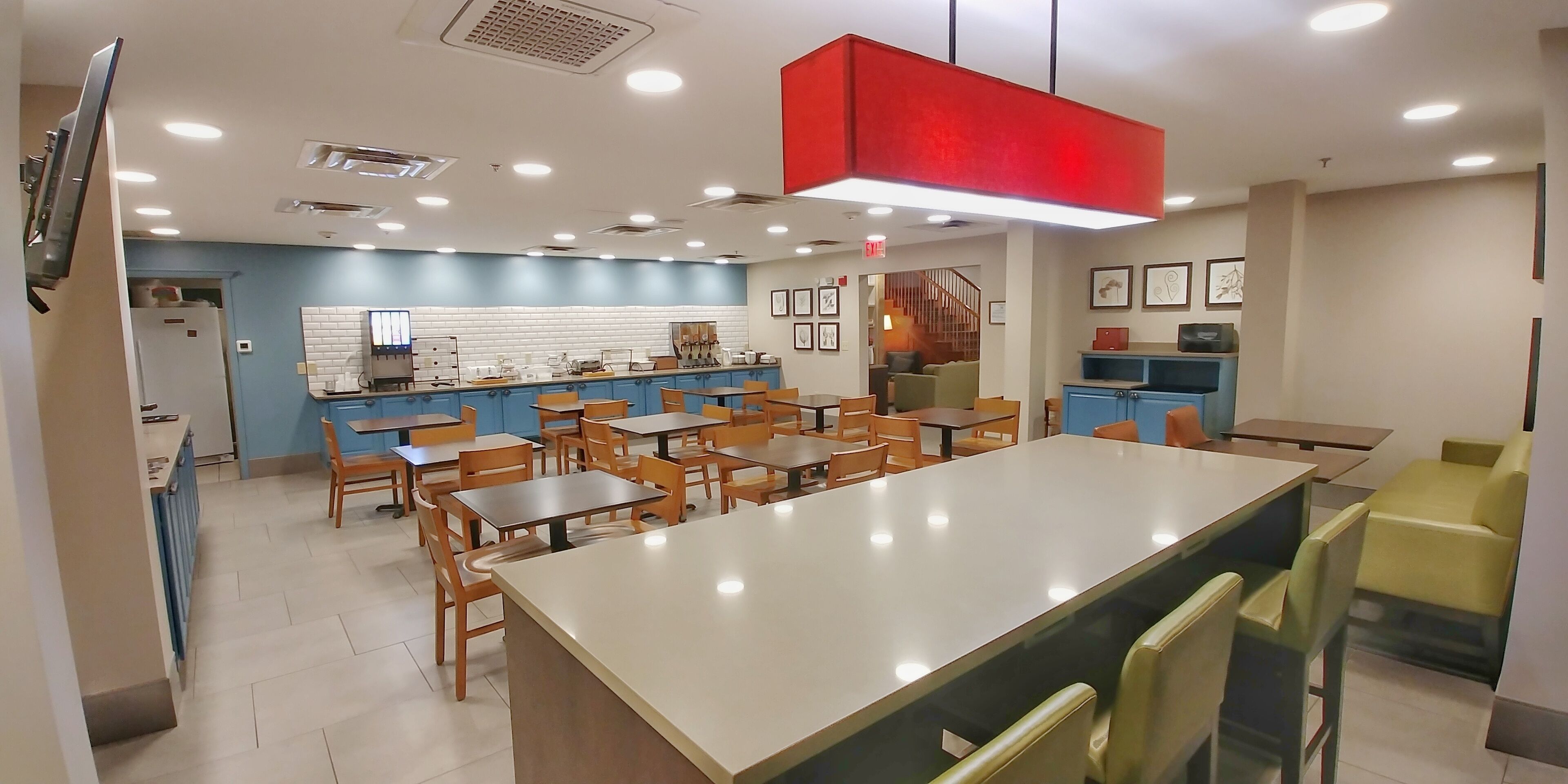 Un restaurante moderno con una isla central, mesas y sillas de madera.