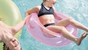 Una persona flota en un círculo rosa hinchable en una piscina.