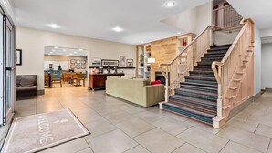 Una sala de estar moderna con una escalera, un sofá, un comedor y una cocina al fondo.