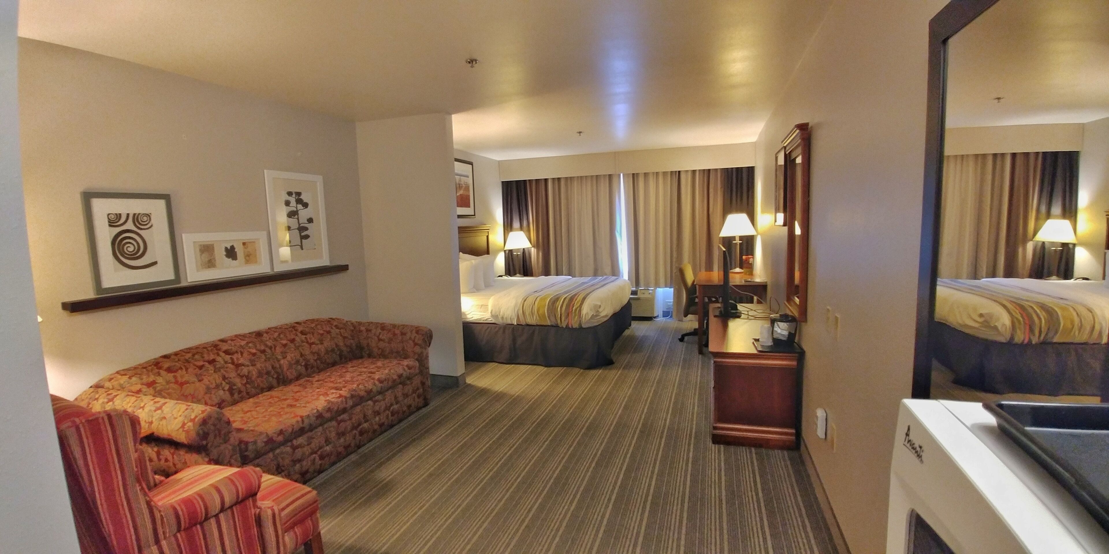 Habitación de hotel con sofá, dos camas, escritorio y espejo.