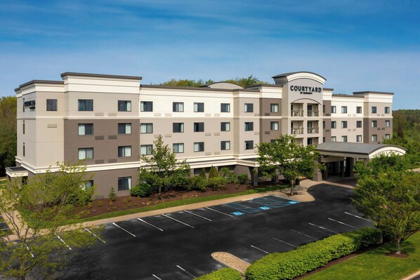 A Courtyard hotel with a modern design, featuring a parking lot and landscaped areas.