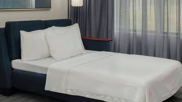 A neatly made bed with white linens in a hotel room.