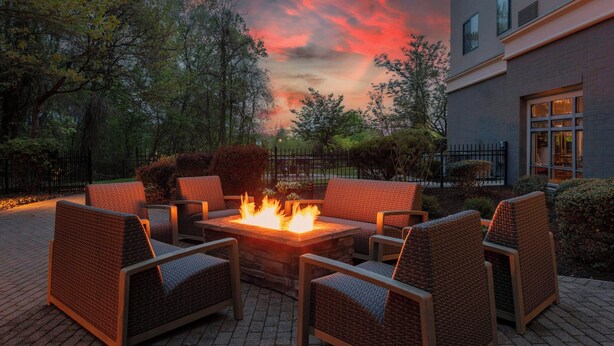 An outdoor seating area with wicker chairs and a central fire feature. - Courtyard by Marriott Pittsburgh Greensburg (Greensburg)