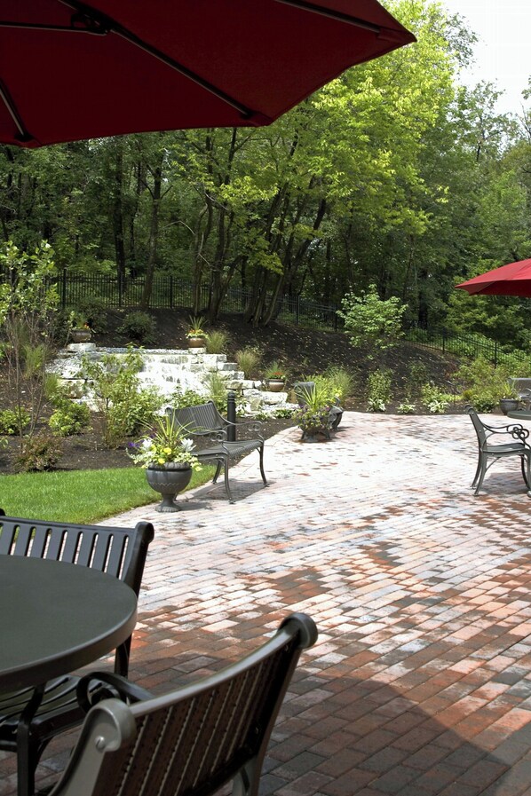 Relax in a serene outdoor space with a brick pathway, seating area, and lush greenery.